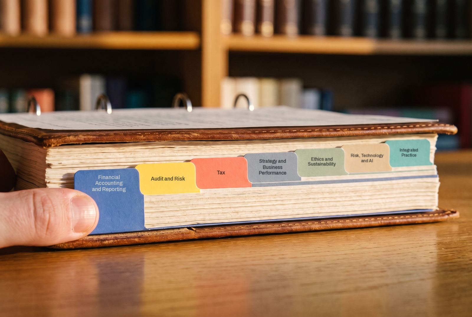 A ring binder with coloured index tabs labelled with subject names, a thumb about to flick the first tab